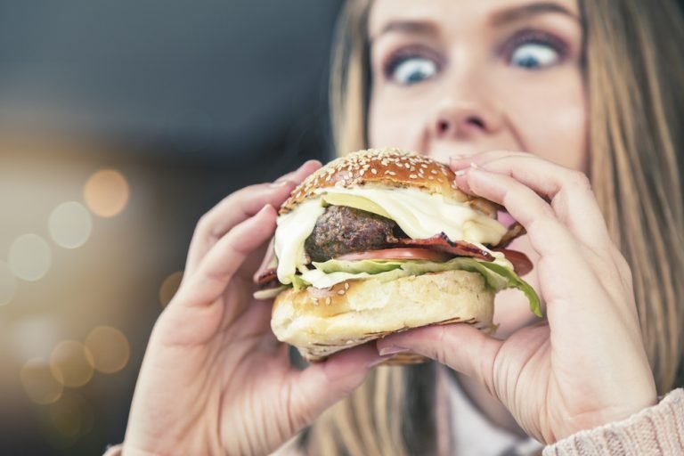 Wide-eyed girl looks down at enormous burger