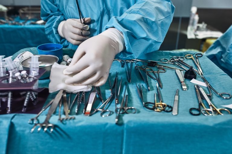 Surgical instruments in the operating room, the surgeon's assistant arranges them on a sterile takani. The concept of medecine, surgery, sterile area. Plastic surgery. Selective focus.