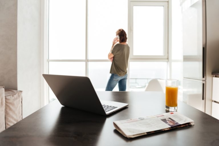 Photo of table with laptop computer, juice, newspaper
