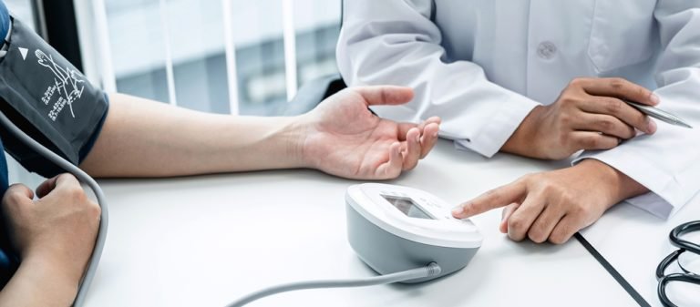 Doctor press blood pressure monitor to measure patient blood pre