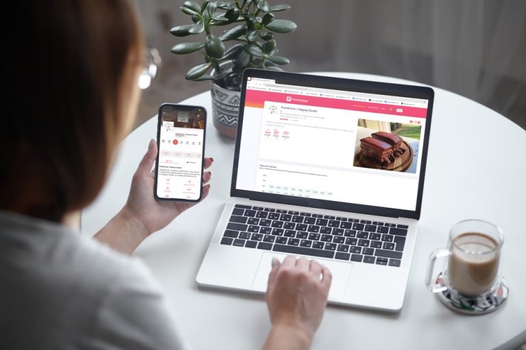 Mockup white screen laptop and mobile phone woman using computer while sitting at table at home, back view