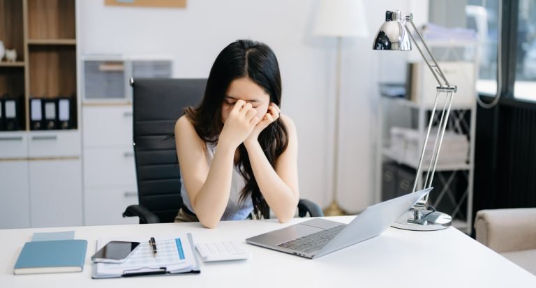 Overworked young Asian businesswoman office worker suffering fro