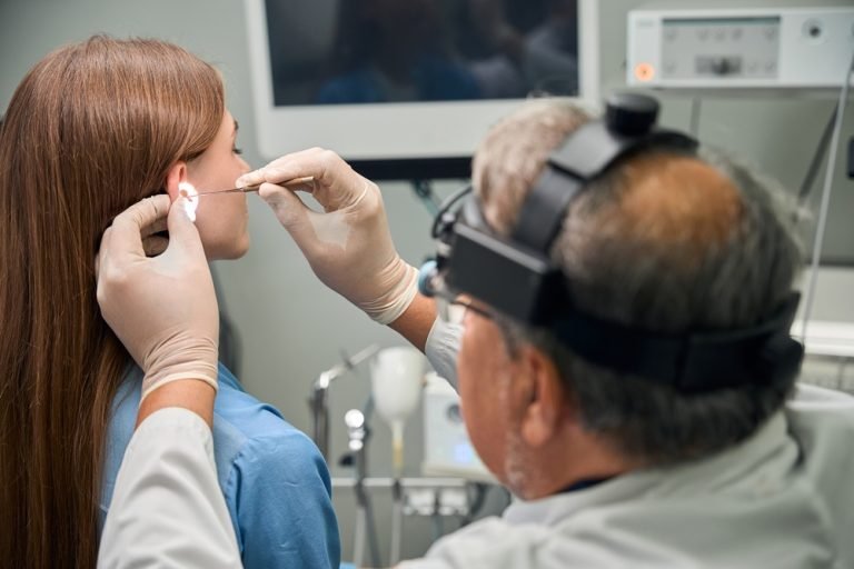 Adult doctor carefully inserting an ear tool