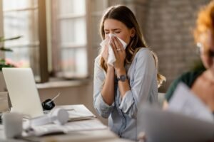 Young businesswoman using a tissue while sneezing in the office.