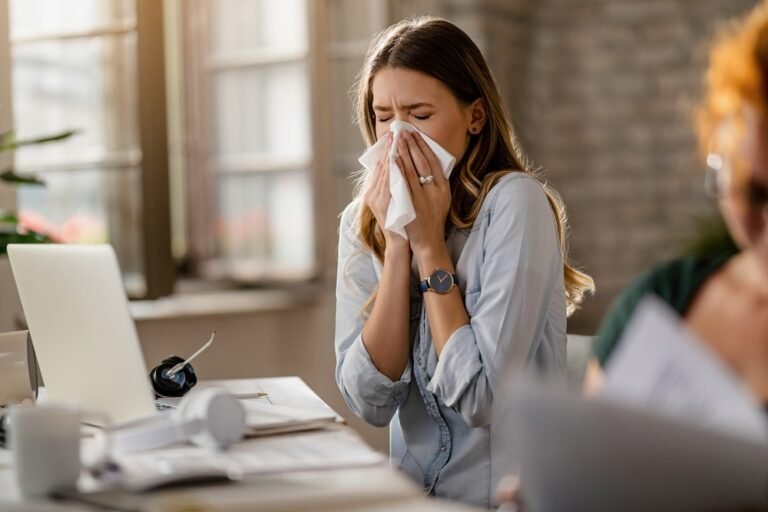 Young businesswoman using a tissue while sneezing in the office.