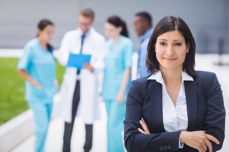 Portrait of smiling female doctor standing with arms crossed in hospital premises
