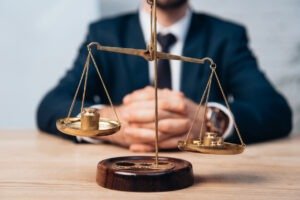selective focus of golden scales near lawyer with clenched hands