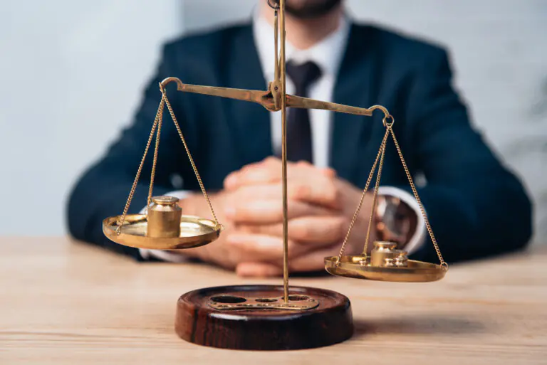 selective focus of golden scales near lawyer with clenched hands