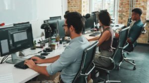 Multiracial team. Back view of busy employees working on computers while sitting at desk in modern open space